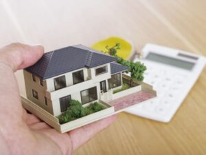 手に持った住宅模型と電卓