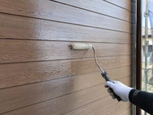 木目柄の外壁材にクリヤー塗料を塗布する施工写真